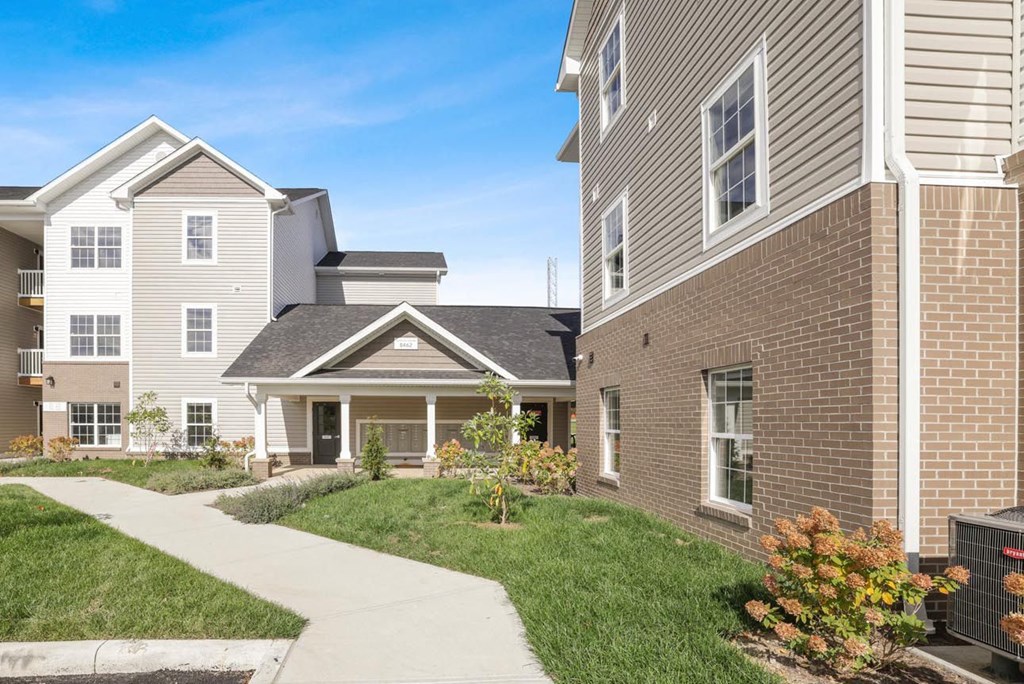 a sidewalk in front of two buildings with grass
