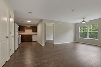 an empty living room and kitchen with wood floors