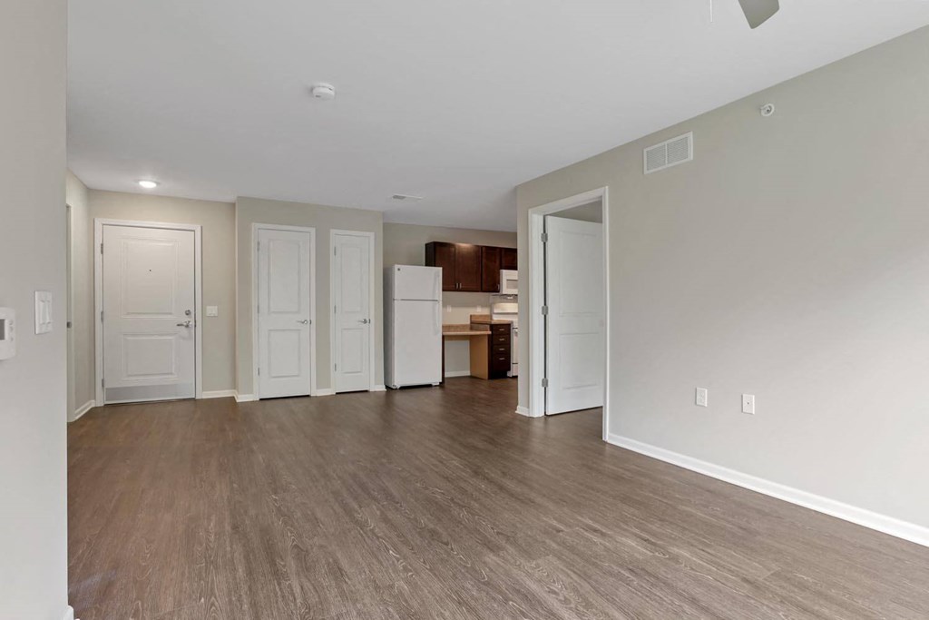 the living room and kitchen of an empty house with a wood floor