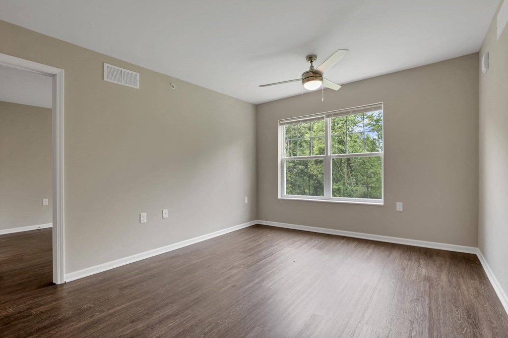 an empty living room with wood floors and a window