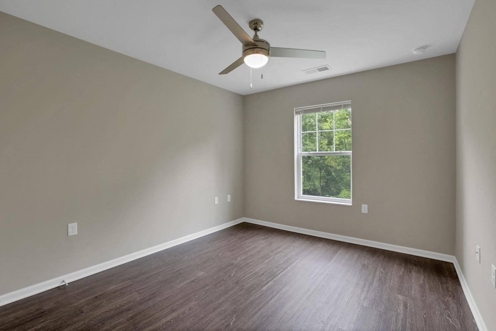 an empty living room with wood floors and a ceiling fan