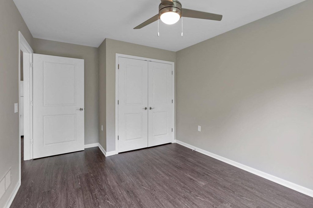 an empty living room with wood floors and a ceiling fan