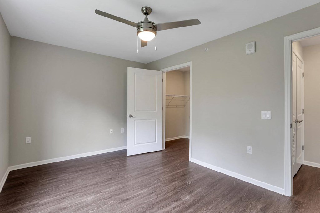 an empty living room with a ceiling fan and a closet
