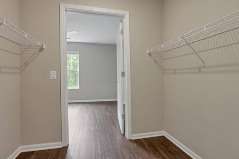 a bedroom with a closet and a door open to a room with wood flooring