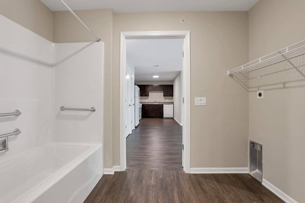 a bathroom with a shower and a bath tub and a hallway to a kitchen