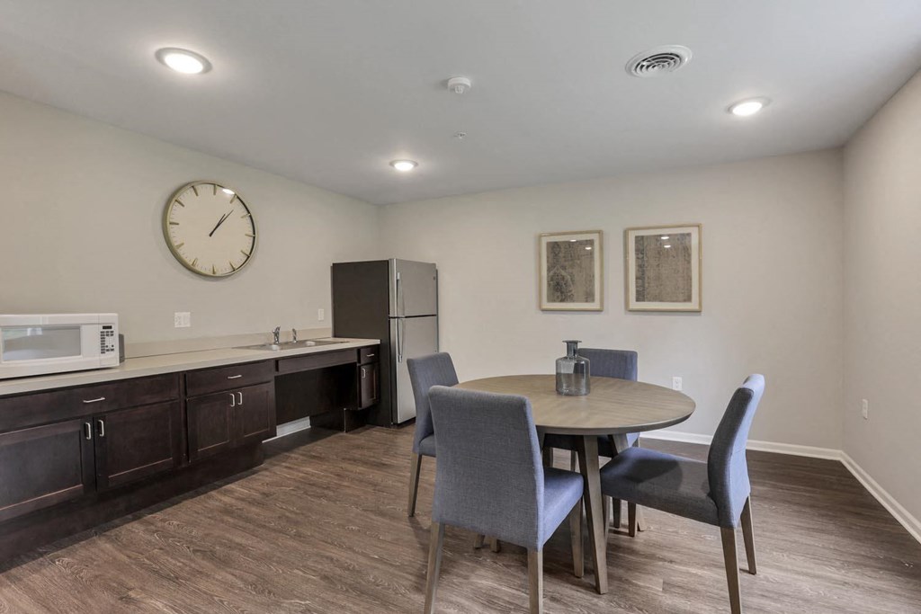 a dining room with a table and chairs and a refrigerator and microwave