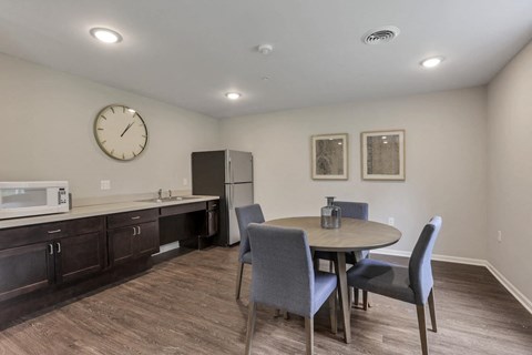 a dining room with a table and chairs and a refrigerator and microwave