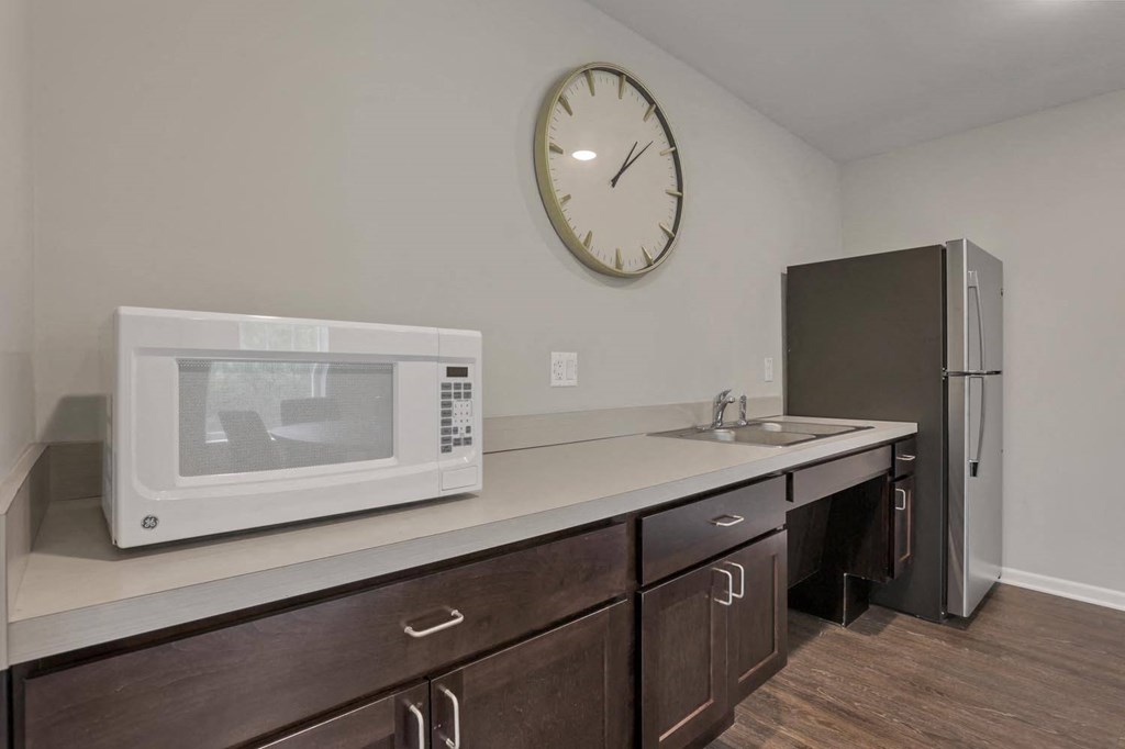 a kitchen with a microwave and a sink and a clock