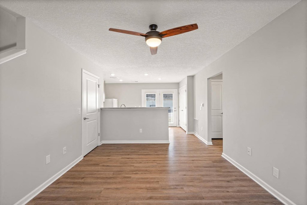 A room with a ceiling fan and wooden flooring.