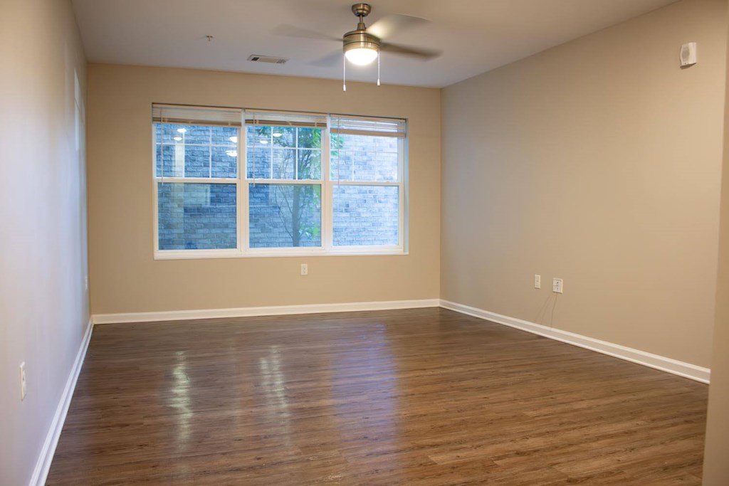 Empty room with a window and wooden floor.