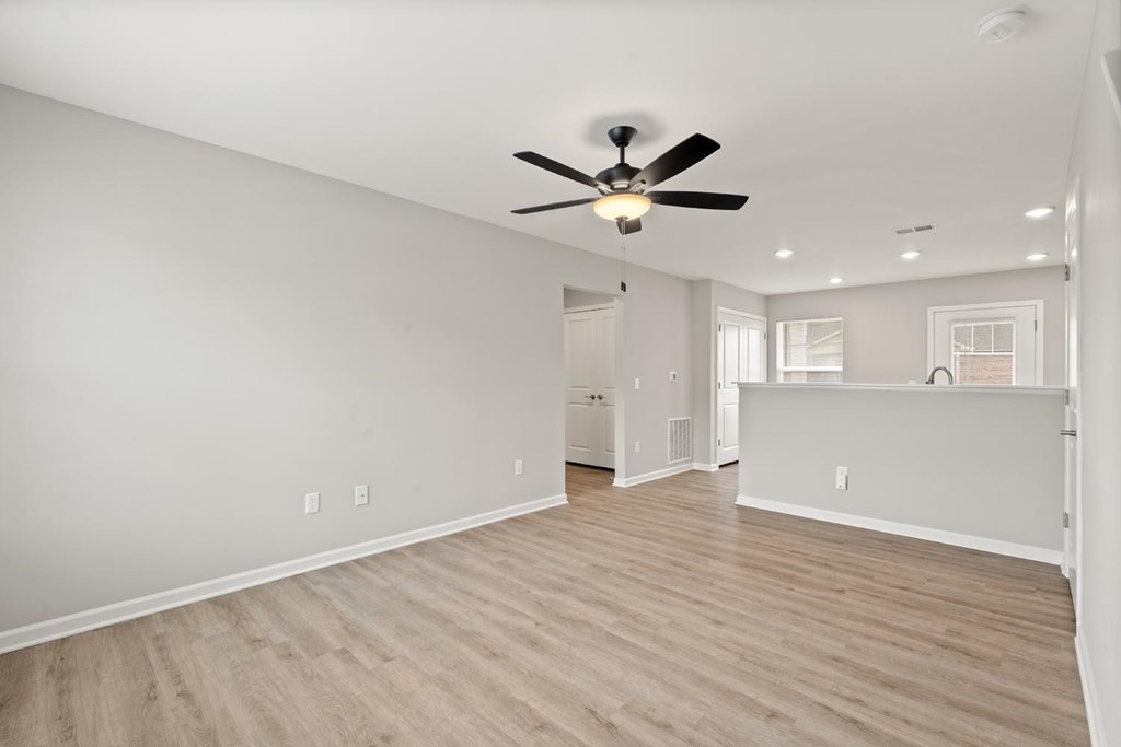 A spacious room with a ceiling fan and light fixture.