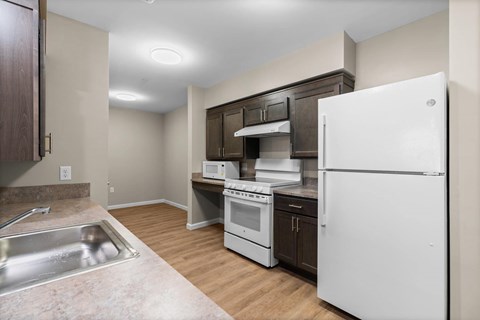 A kitchen with white appliances and wooden cabinets.