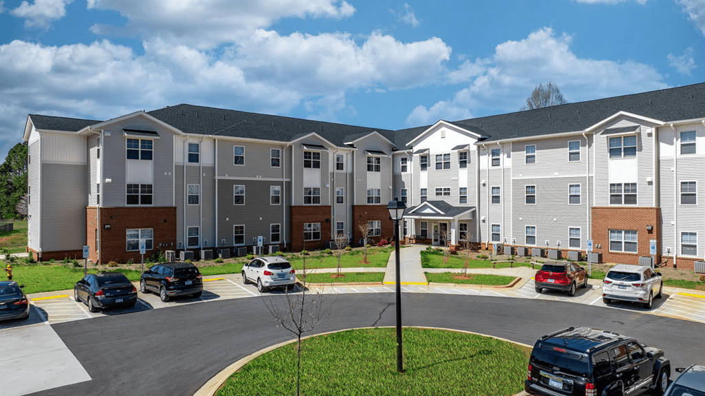 an exterior view of an apartment building with cars parked in a parking lot