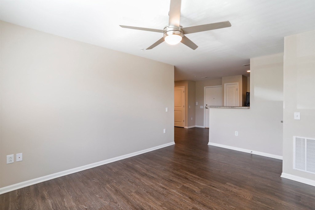 an empty living room with a ceiling fan and hardwood floors