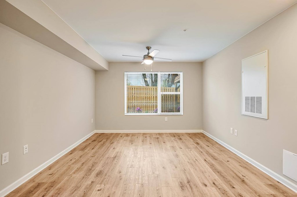 A room with wooden flooring and a window with blinds.