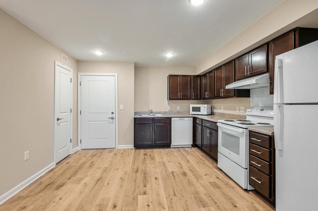 A kitchen with white appliances and brown cabinets.