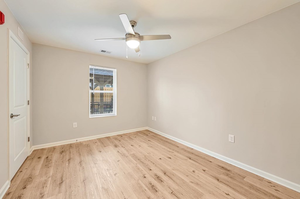 A room with a ceiling fan and a window with a view of a building.