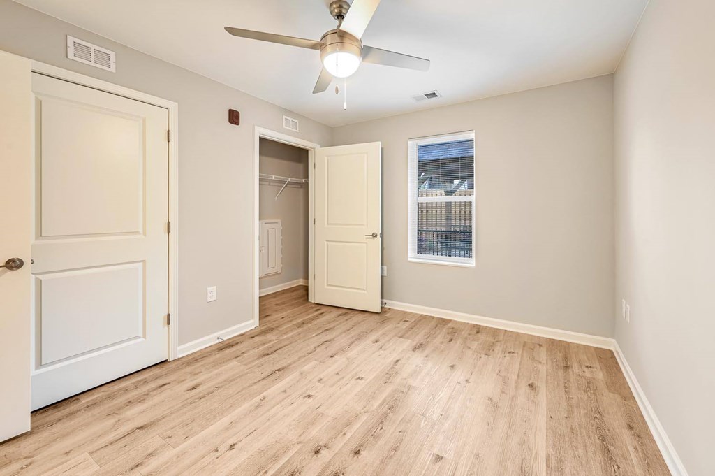 A room with a ceiling fan and wooden flooring.