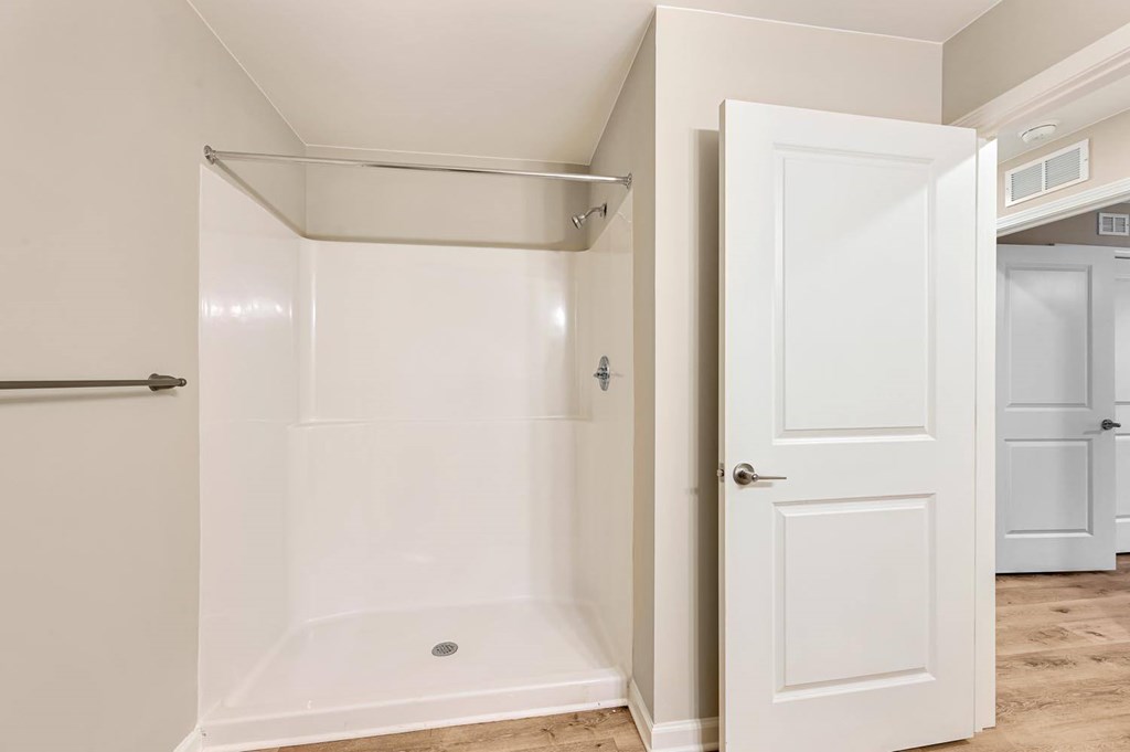 A white bathroom with a walk-in shower and a white door.