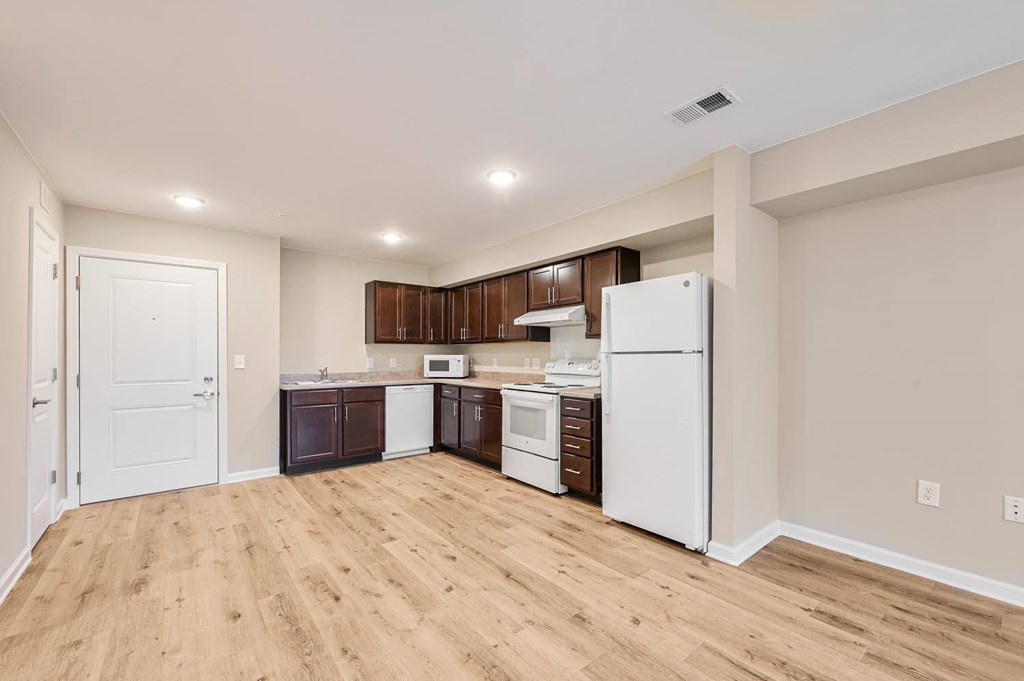 A kitchen with white appliances and wooden floors.