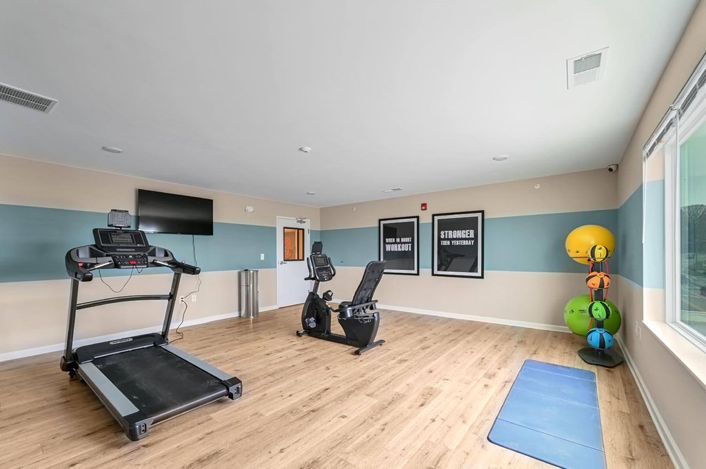 A room with a treadmill, exercise bike, and a yoga mat.