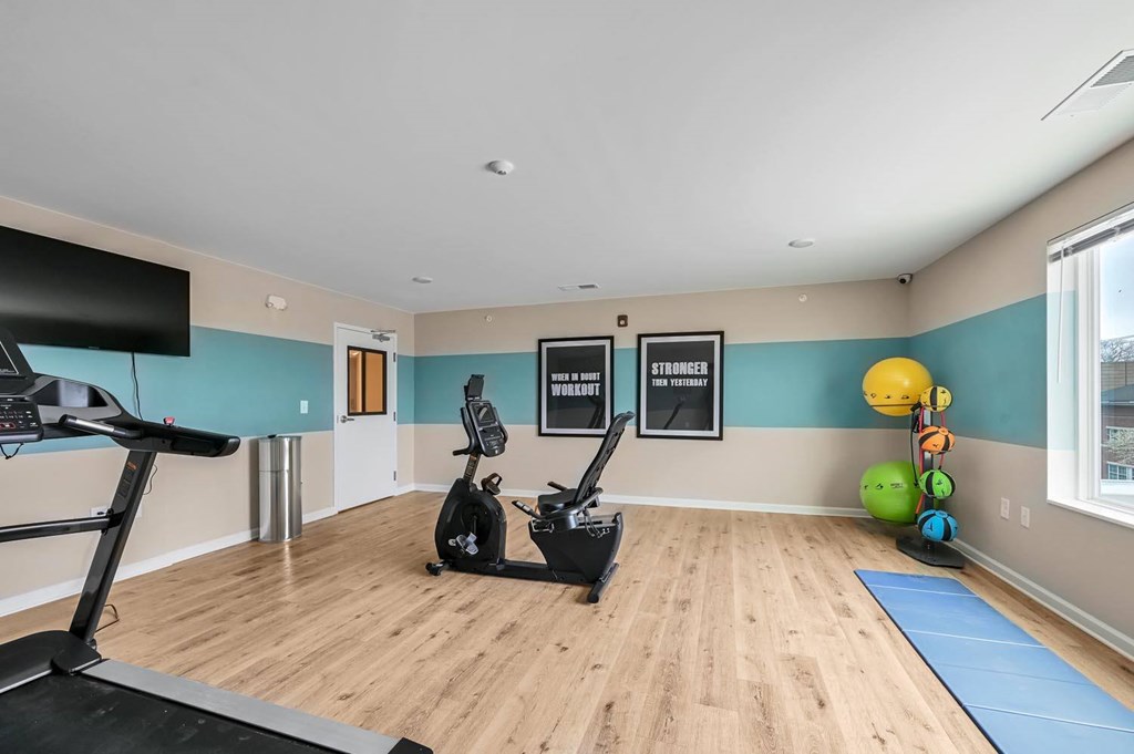 A room with a treadmill, exercise bike, and a yoga ball.