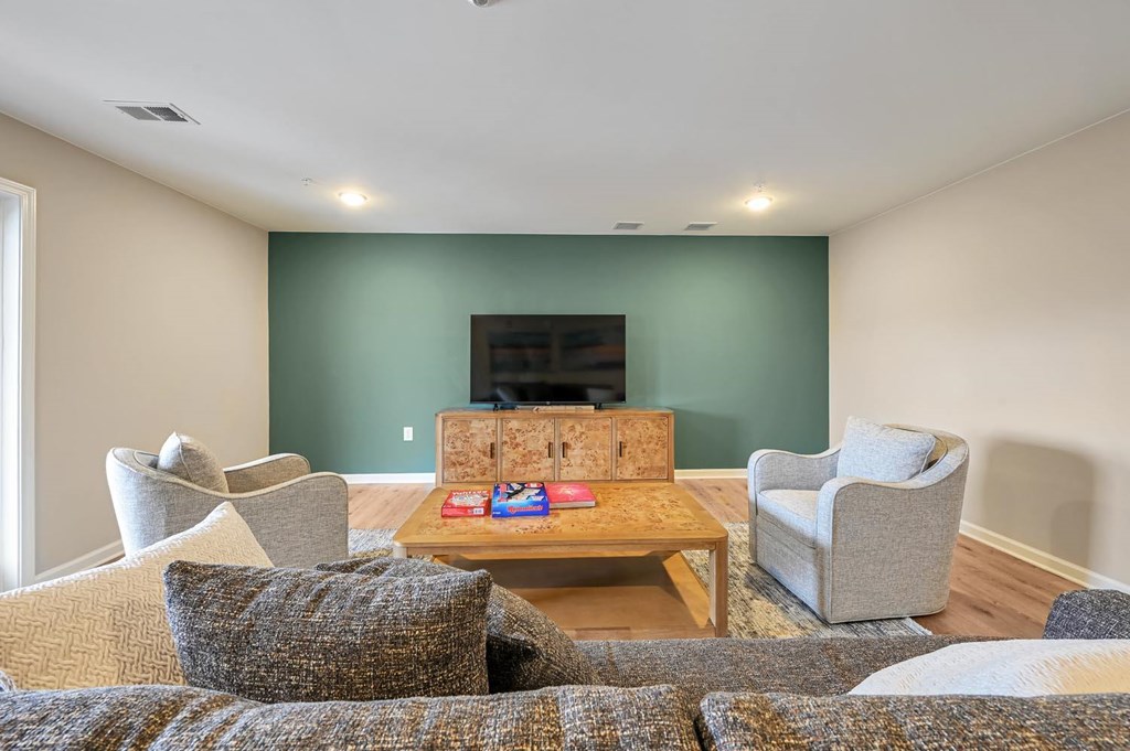 A living room with a couch, chairs, and a television.