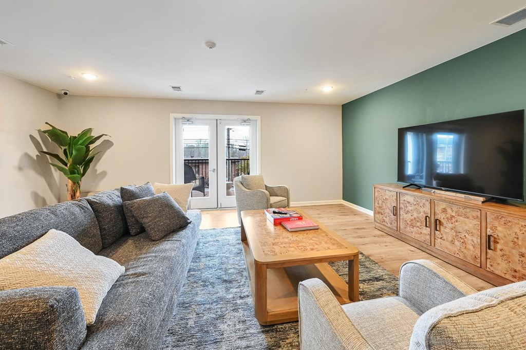A living room with a grey couch, a wooden coffee table, and a television.