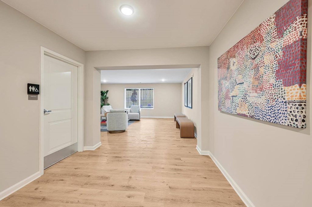 A hallway with a large artwork on the wall and a door on the left.