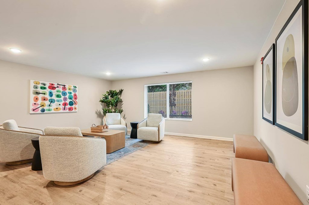A living room with a white couch, a chair, a coffee table, and a painting on the wall.