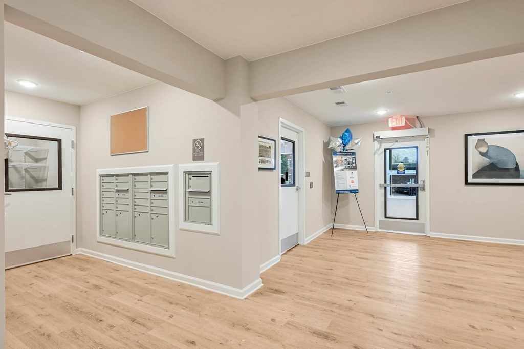 A room with a wooden floor and white walls, with a framed picture on the right wall.