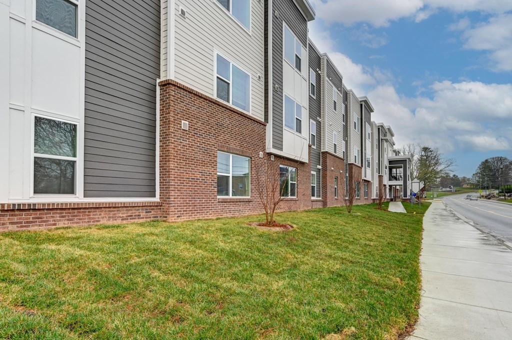 A row of apartment buildings with a sidewalk in front.