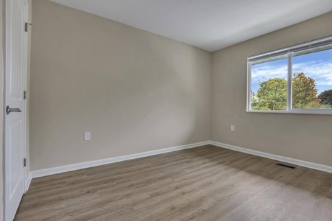 A room with a window showing trees and sky outside.