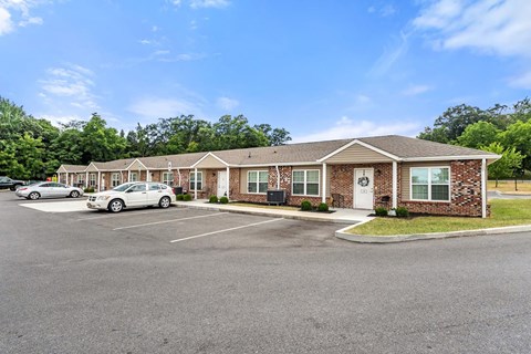 a parking lot in front of a brick building with cars in front