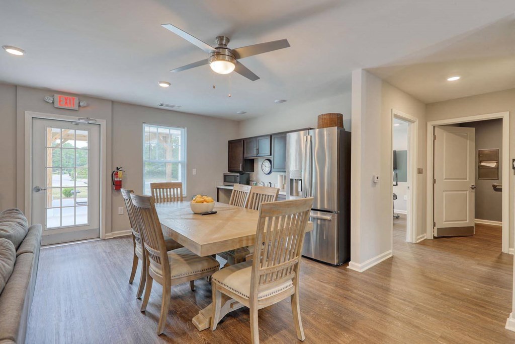 a dining room and kitchen area with a table and chairs and a ceiling fan
