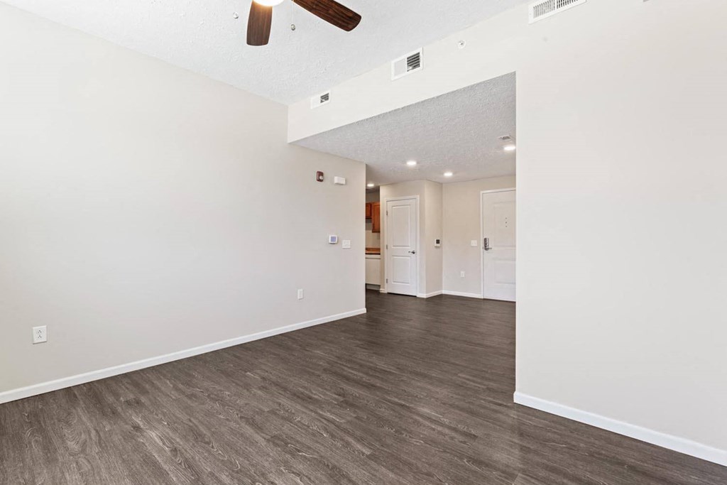 a living room with white walls and a ceiling fan