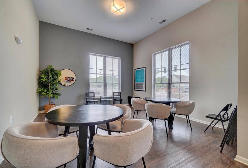 a room with tables and chairs and two large windows