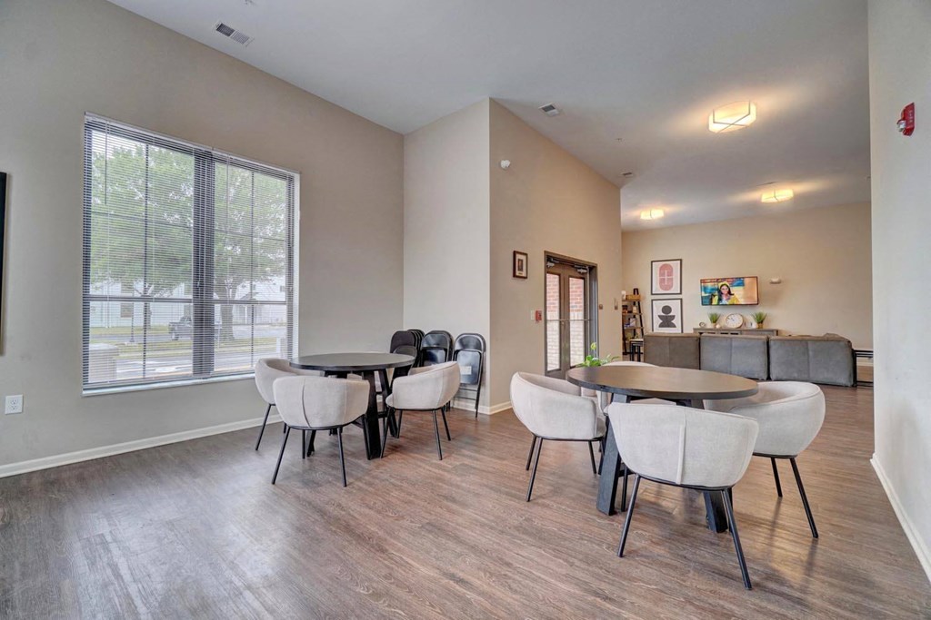 a room with a table and chairs and a large window
