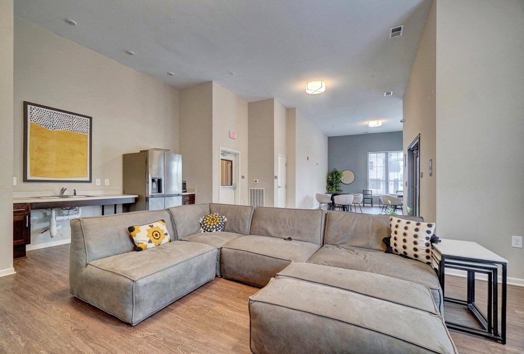 a large couch in a living room with a kitchen in the background