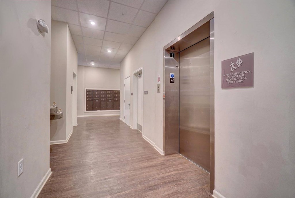 a photo of a corridor in a building with elevators and a sign on the wall