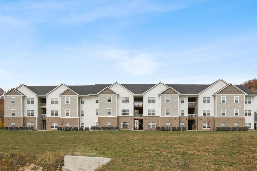 an apartment building with a field in front of it