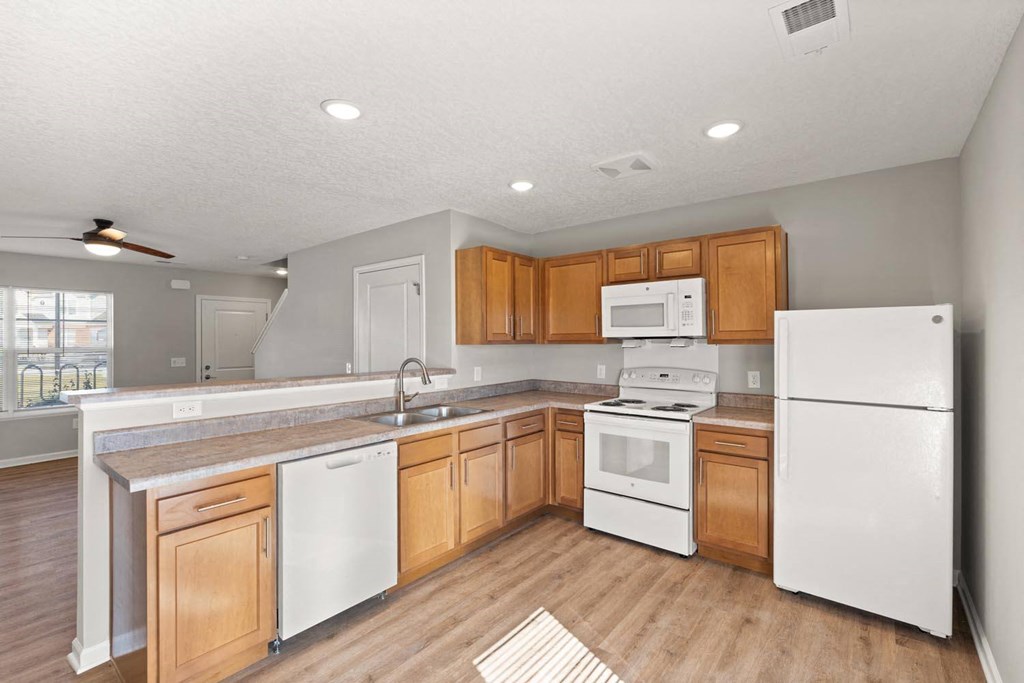 A kitchen with white appliances and wooden cabinets.