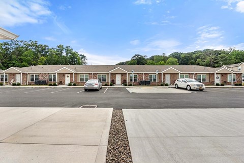 an empty parking lot with cars in front of an apartment building