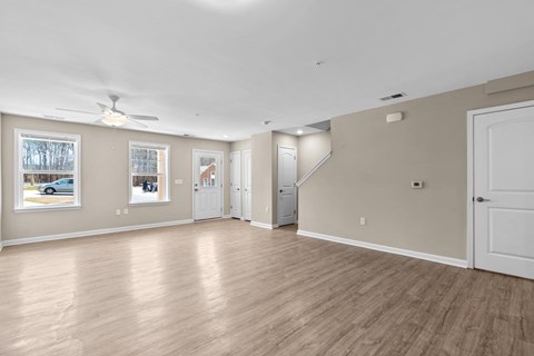 A spacious room with light wood flooring and white walls.