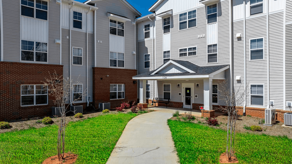 a pathway leading to an apartment building with a porch