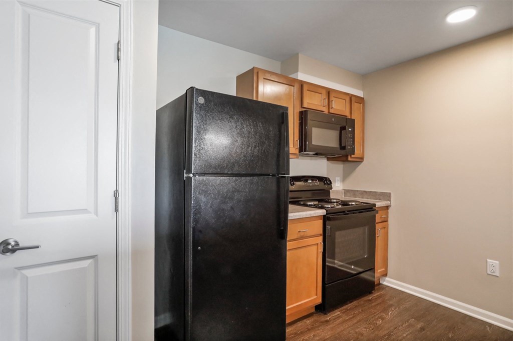 a kitchen with a black refrigerator freezer next to a stove top oven