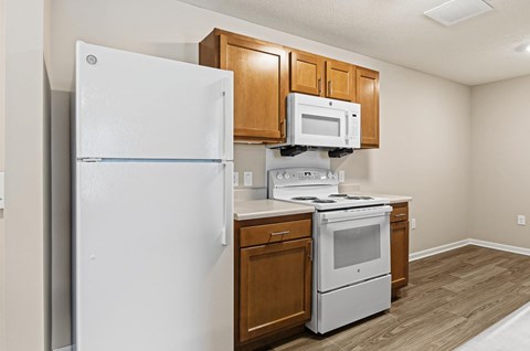 A white refrigerator is in a kitchen with wooden cabinets.