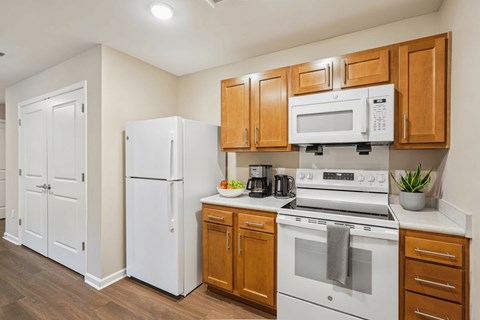 A kitchen with white appliances and wooden cabinets.