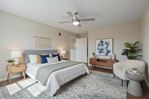 A bedroom with a bed, chair, and a rug.