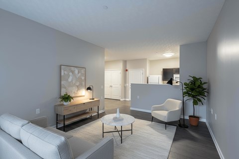 A living room with a white couch, a coffee table, and a potted plant.